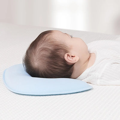 Baby resting on a light blue CottonHead Pillow designed to support and protect head shape. Made of breathable, soft material for safe infant sleep.